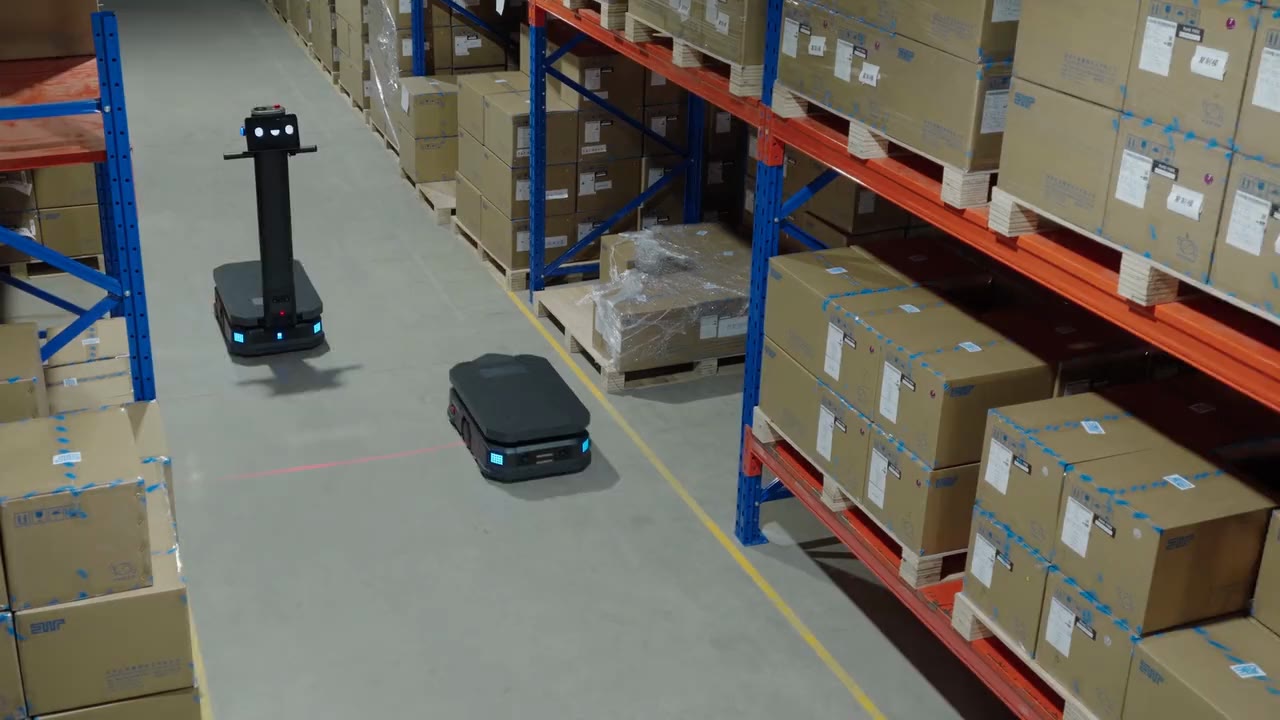A Pudu T600 transport robot hauling cart loads down a warehouse aisle