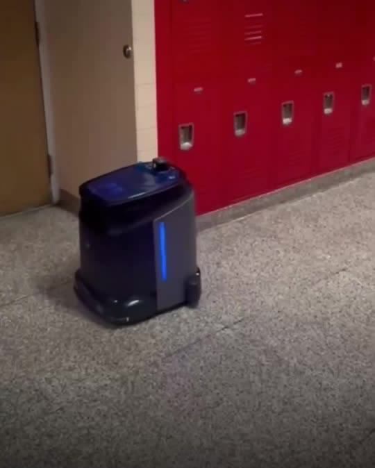 An autonomous floor-cleaning robot in a school hallway